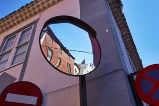 Distorted reflection of houses and road signs in a convex mirror, UNESCO World Heritage Old Town of