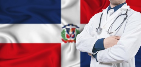Dominican Republic healthcare concept. Male doctor on Dominican Republic flag. Doctor with crossed