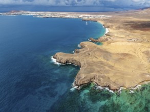 Coast with Playa de Papagayo beach and blue sea, arid landscape of Los Ajaches Natural Park, aerial