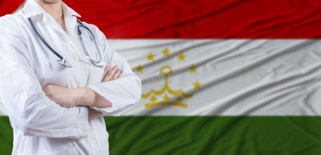 Doctor with crossed arms on Tajikistan flag. Tajikistani health and care concept. Female doctor on