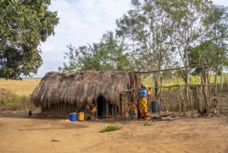 Mother and child in front of a simple traditional clay hut in a Sadaani village, Tanga, Tanzania