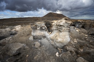 Eroded rock formations in volcanic landscape with dramatic cloudy skies, Ciudad Estratificada or