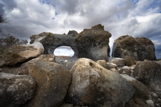 Eroded rock formations with rock tunnels, volcanic landscape with dramatic cloudy skies, Ciudad