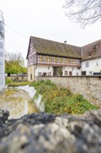 Half-timbered house with old walls and adjoining ensemble of buildings in an autumnal village