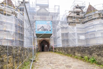 Entrance gate of a medieval building with scaffolding, surrounded by an old sandstone wall, Glatt