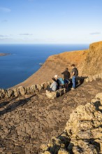 Tourists sitting on a bench on the observation deck at the Mirador del RÃ­o viewpoint, in the