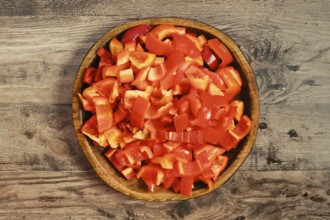 Freshly chopped red bell peppers in a wooden bowl. The chopped pieces are neatly arranged, ready to
