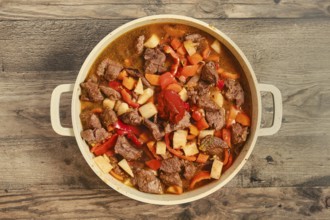 Tender beef chunks are mixed with vegetables like carrots, bell peppers and celery root in a pot.