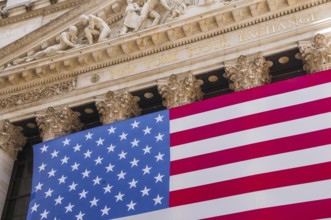 Facade of the New York Stock Exchange, stock exchange with USA national flag on Wall Street,
