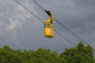 Yellow cable car floating over green trees under cloudy sky, cable car cabin, Kutaisi, Imereti