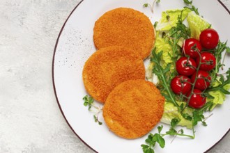 Crispy fried fish cutlets, fish burgers, on a white plate, with fresh lettuce leaves, arugula and
