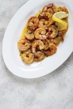 Fried tiger prawns, jumbo, in garlic sauce, in butter, with herbs, on a white plate, homemade, no