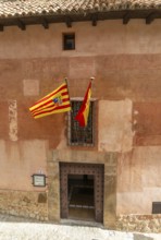 Alberque hostel building with flags flying, historic buildings in medieval village of AlbarracÃ­n,