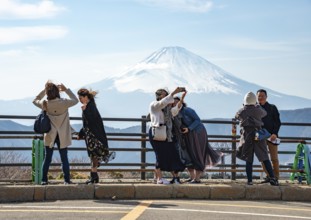 Tourists enjoy the view and take pictures, view of the snow-covered summit of Mount Fuji volcano in