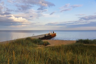 Coastline with beach, grasses on the shore, bathers at the jetty, summer in Ystad, evening sun,