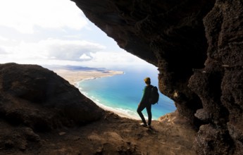 Tourist in the Cueva de las Cabras cave, young woman enjoying the view from the Risco de Famara