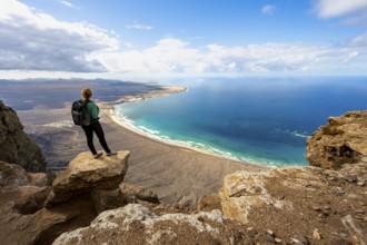 Young woman enjoying the view from the Risco de Famara cliffs to Famara beach, Playa de Famara with