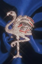 Pelican as rhinestone decoration with blur shot on blue velvet, Bavaria, Germany