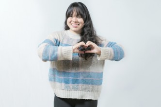 Beautiful asian girl making heart shape isolated. Happy asian woman making heart shape with hands