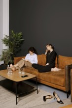 Two friends enjoy a cozy afternoon on a comfortable sofa in a modern living room. One reads