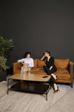Two individuals engage in a conversation while sitting in a contemporary living room. The setting