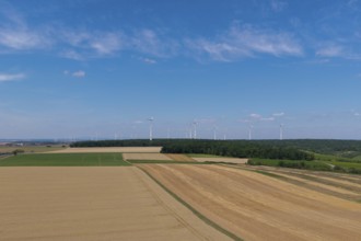 Wide fields with a wind farm on the horizon, under a clear blue sky, near Volkach, aerial view,