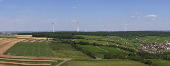 Panoramic view of fields with a wind farm in the background under a blue sky, aerial view,