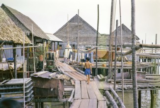 Wooden plank walkway past attap houses of fishing village on stilts, Singapore, southeast Asia 1963
