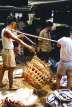Weighing baskets of fish at the old fish market, Johor Bahru, Malaysia, Southeast Asia 1963