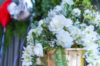 Elegant white roses and greenery adorn a golden vase, adding a touch of romance to a wedding