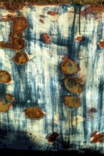 Textured surface revealing rust patterns on a weathered metal sheet in an outdoor setting during