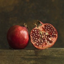 Pomegranate halves revealing juicy seeds on rustic wooden surface