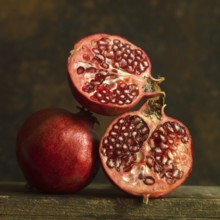 Pomegranates cut in half with seeds exposed on wooden surface in soft lighting