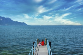 Switzerland. Mother and daughter sitting on a pontoon on the shores of Lake Geneva in Montreux