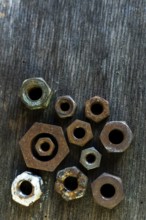 Collection of rusted metal nuts arranged on a weathered wooden surface highlighting unique textures
