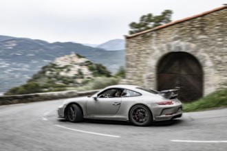Dynamic photo with reduced colours of Porsche 911 GT3 driving fast through legendary curve known