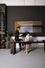 Women collaborating in a modern office space while discussing project ideas during daylight hours