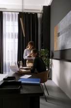 In a contemporary office, two women engage in a productive discussion while reviewing documents.