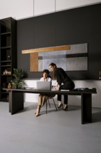Two professionals engage in a collaborative effort at a sleek office workspace. One woman is seated