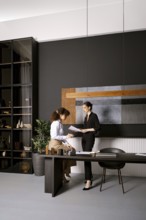 Two businesswomen are looking for a solution of an issue reading papers in an office. One woman