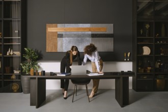 Two business professionals are engaged in a collaborative discussion around a laptop at a sleek