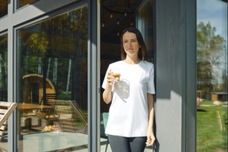 The woman went to the terrace of a country house with a glass of juice and enjoys silence and fresh