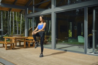 A woman wearing athletic attire is engaged in a warm-up exercise, raising one knee while standing