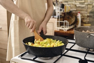 Cooking chopped bell peppers in a modern kitchen with natural light streaming through the window
