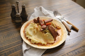 A plate filled with creamy mashed potatoes topped with tender pieces of meat and colorful
