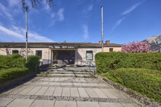 St. Nikolaus parish hall, flagpoles, hedge, stairs, paving slabs, cobblestones, blue sky,