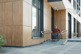 A person in a wheelchair navigates the accessible entrance of a contemporary building, showcasing