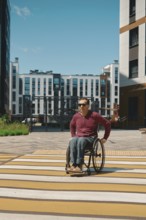 A person using a wheelchair navigates a brightly painted crosswalk in a modern urban area.