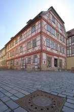 Red Luther House and square manhole cover with town coat of arms, cobblestones, view from below,