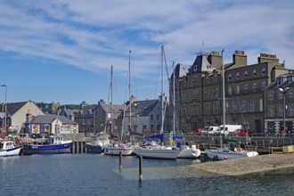 Coastal harbour with sailing boats and historic buildings under a bright blue sky, Kirkwall, Orkney